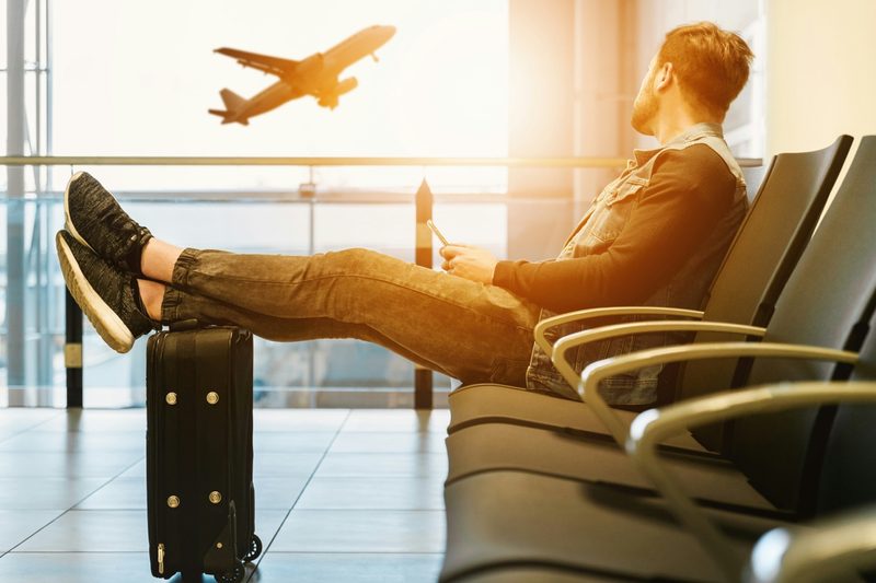 Traveler waiting at airport gate as aircraft takes off